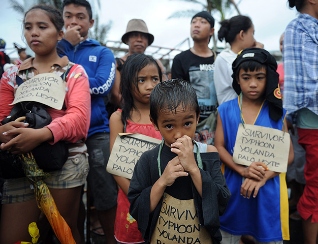 Survivors of the super Typhoon Haiyan, wait for a C-130 military plane at T